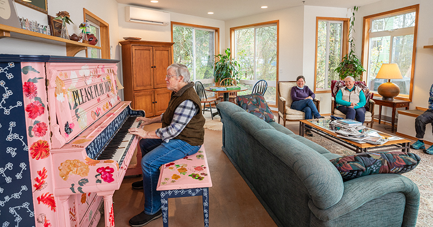 Man playing piano in a common area cooled by a ductless heat pump