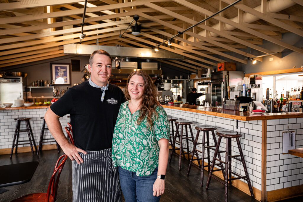 Smiling restaurant owners posing in their dining room.