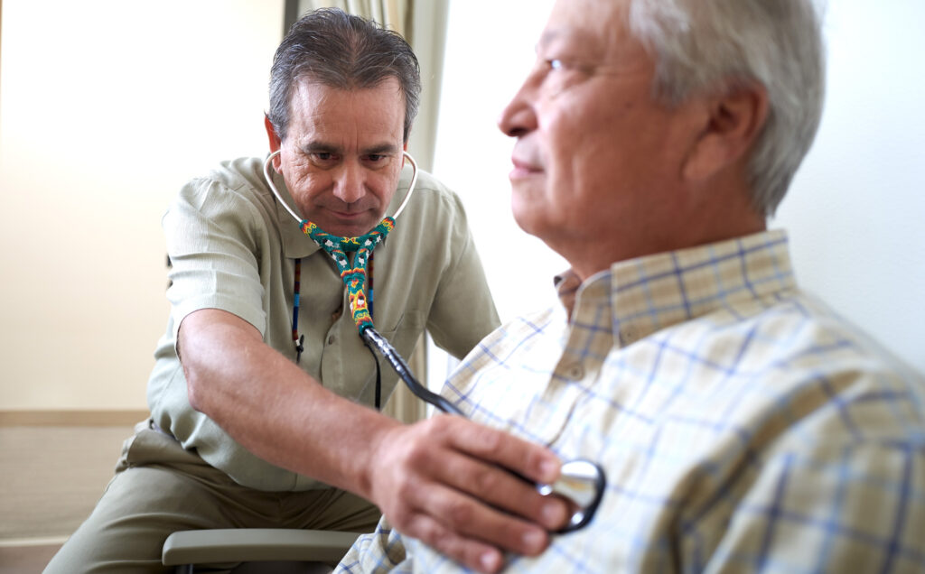 Doctor using a stethoscope over the heart of his patient in an exam room at the Yellowhawk Tribal Health Center