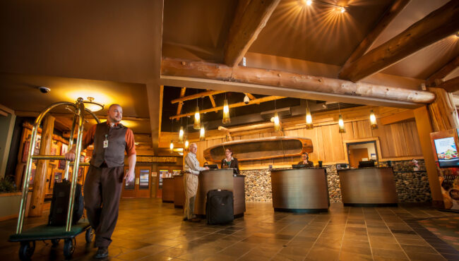 Hotel lobby with bright lighting with a man pushing a luggage cart in the foreground